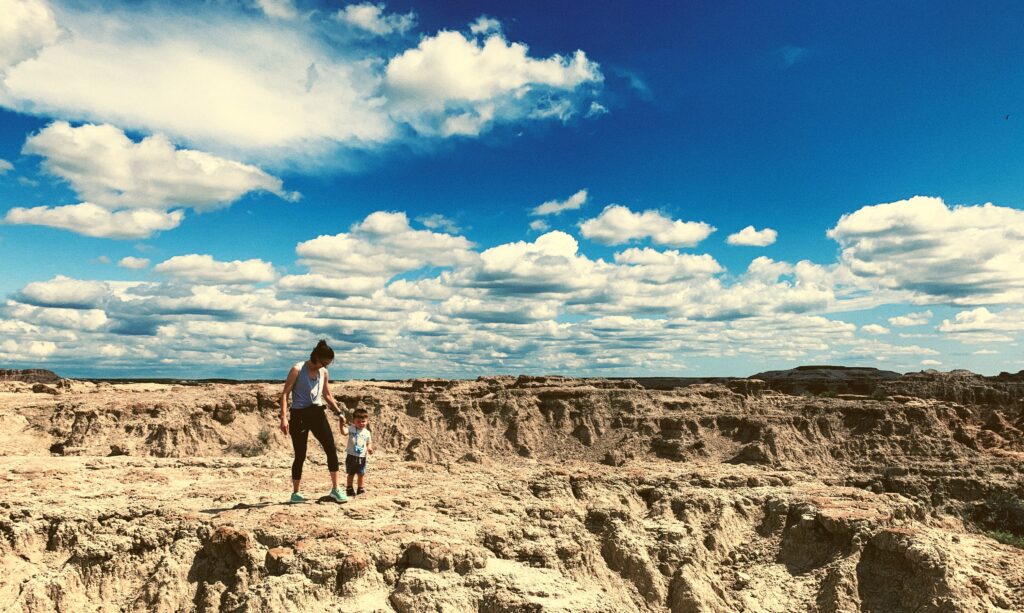 A person and child fossil hunting in the badlands