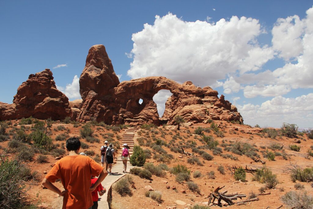 People from behind hiking the desert Arches National Park in Utah